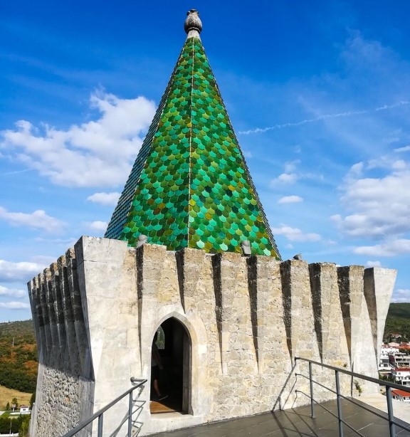 Coruchéu piramidal numa das torres do Castelo de Porto de Mós, com telhas de escama verdes, representando a Casa de Ourém